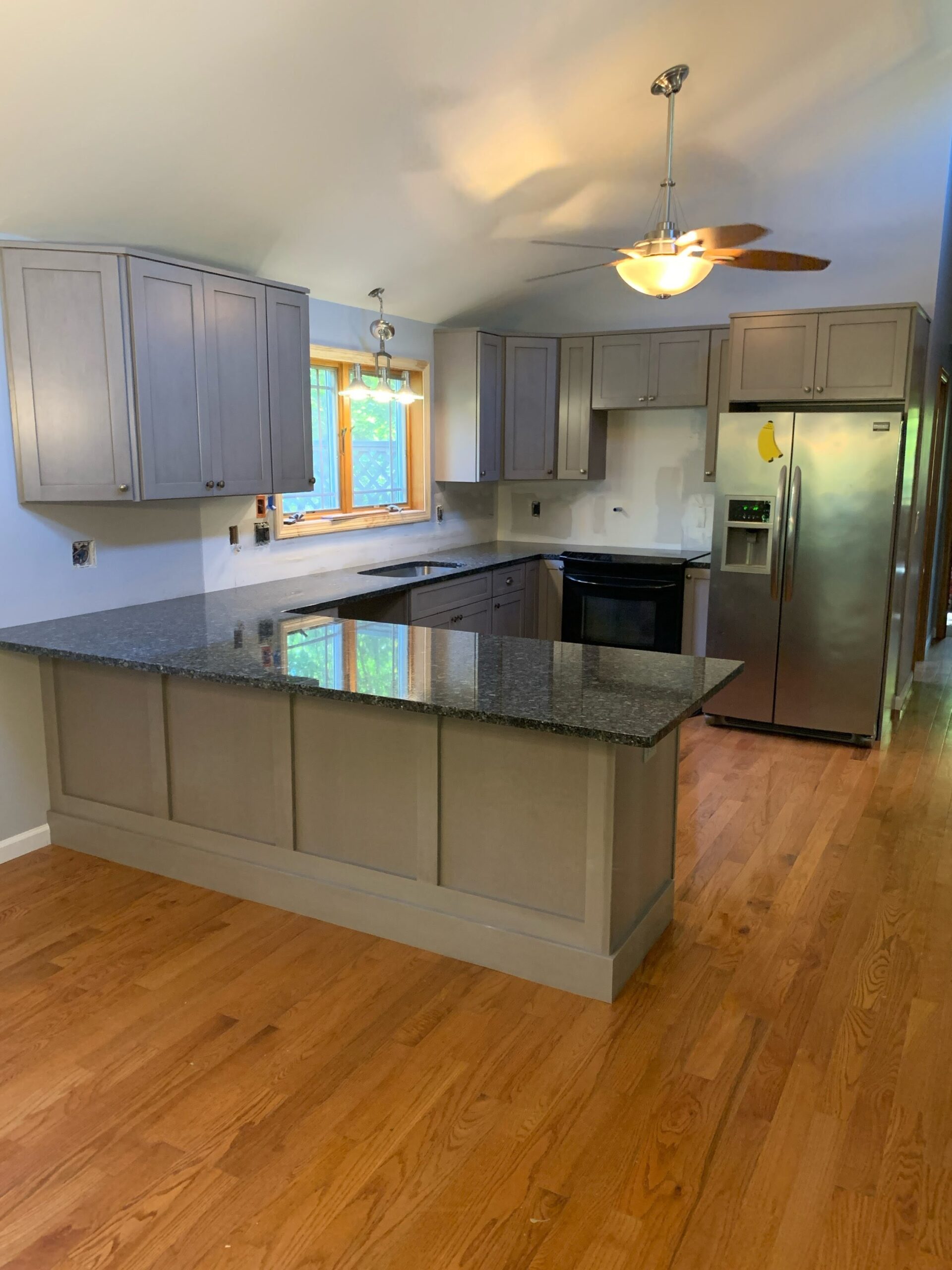 New Kitchen in Vernon Modern kitchen in a newly built in-law suite addition in Vernon, CT, featuring granite countertops, wood flooring, and gray shaker cabinets.